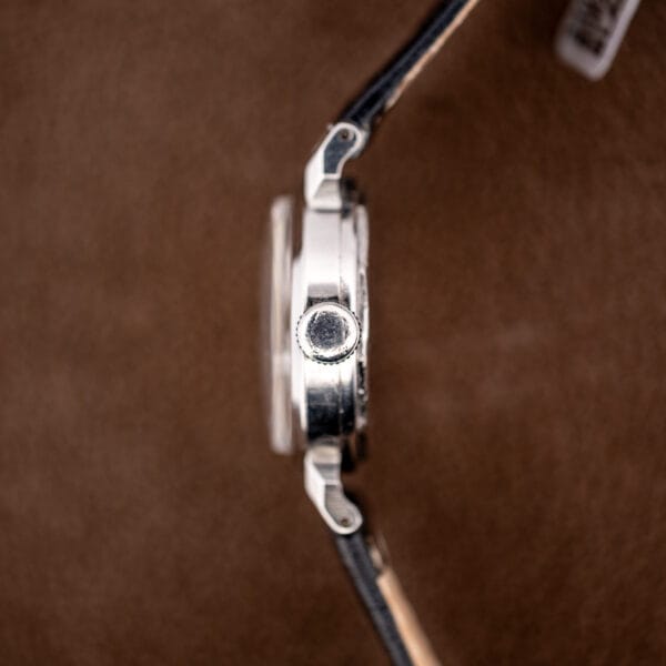 Signed fluted Movado crown and case side, macro detail of the winding crown at three.