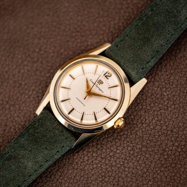 Vintage Girard-Perregaux Gyromatic 33mm gold capped case angled on a forest green Italian suede strap