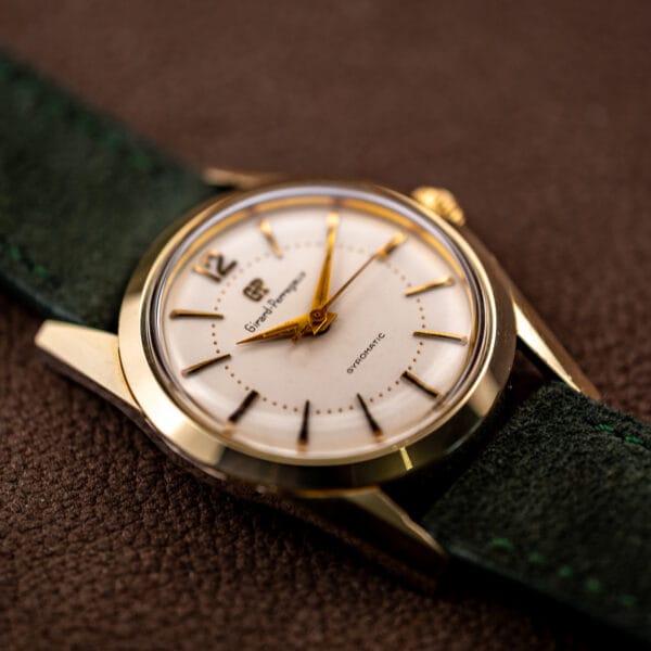 Girard-Perregaux Gyromatic gold capped bezel and tapered faceted lugs against forest green suede