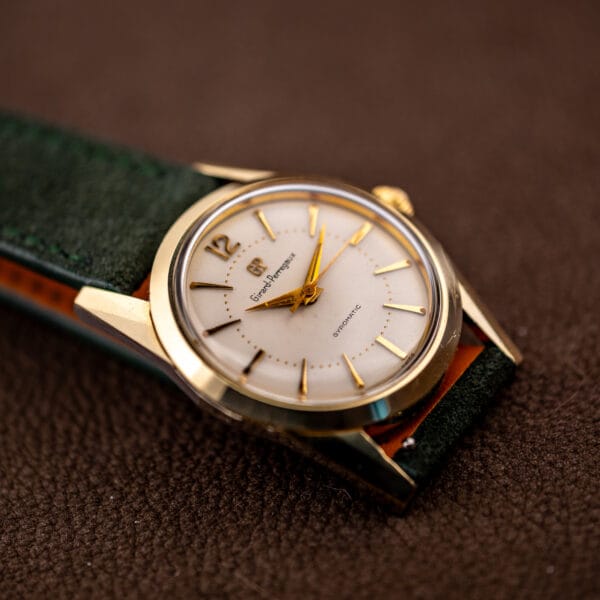 Vintage Girard-Perregaux Gyromatic angled on green suede showing gold capped case and white dial