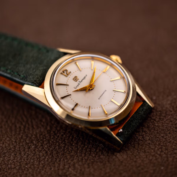 Vintage Girard-Perregaux Gyromatic angled on green suede showing gold capped case and white dial