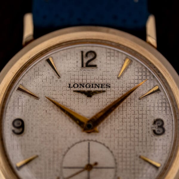 Longines Ref. 1044 dial macro showing fine woven waffle grid, applied gold batons and winged hourglass logo