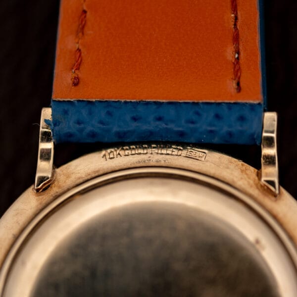 Longines 1044 case flank stamped 10K GOLD FILLED beside blue leather strap and faceted gold lug