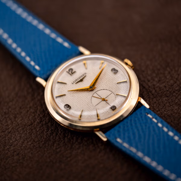 Vintage Longines waffle dial 1044 on blue leather strap, gold filled case against brown leather