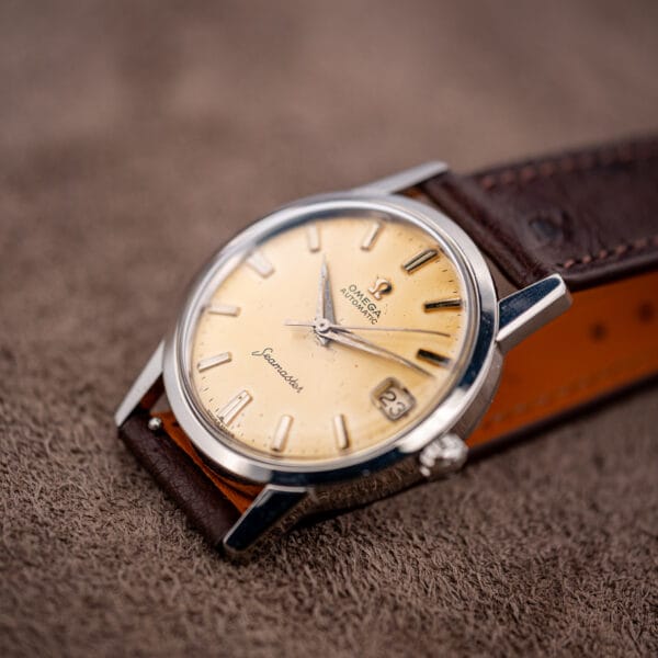 Omega Seamaster 14760 three-quarter view, warm eggshell dial and tapered polished lugs on ostrich strap