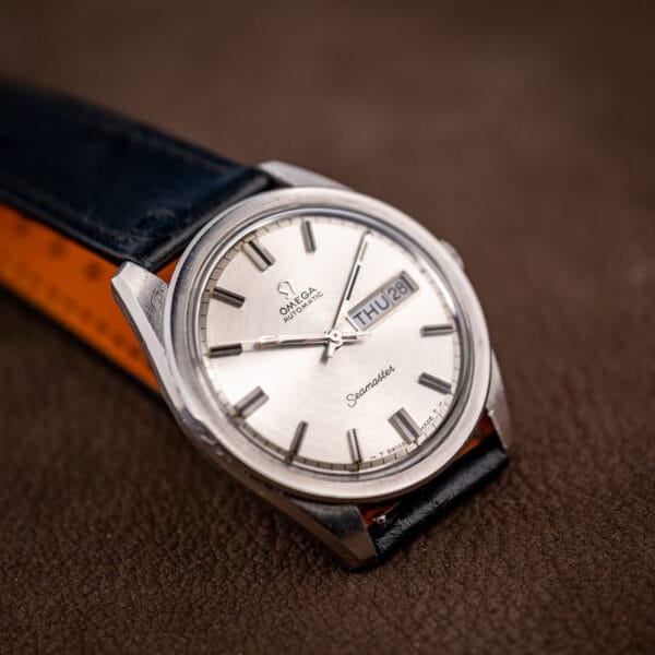 Vintage Omega Seamaster day-date 166.032 with its black ostrich strap unfastened across brown leather