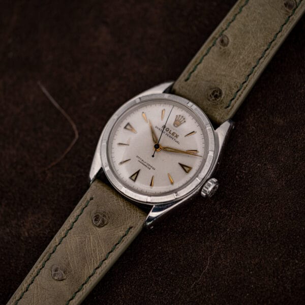 Rolex Oyster Perpetual 6085 resting at an angle, white chronometer dial beside the engine turned bezel