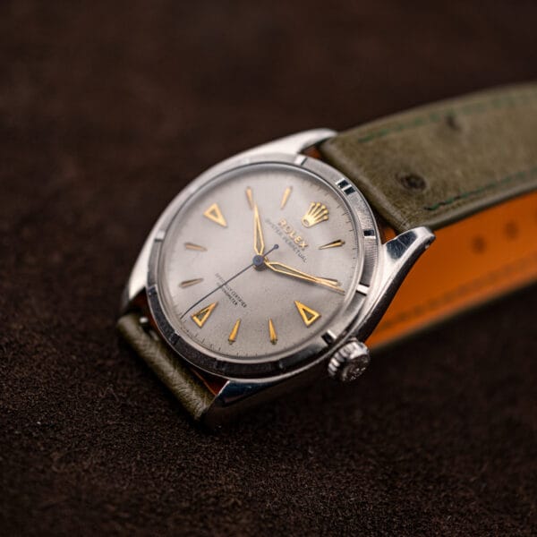 Rolex 6085 Ovettone at a three quarter angle, engine turned steel bezel above the aged white dial