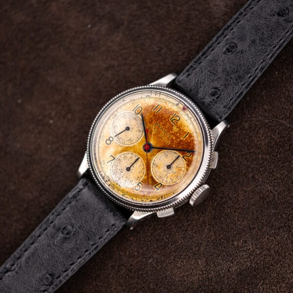 Benrus Sky Chief 37.5mm steel chronograph angled on black ostrich strap over brown suede