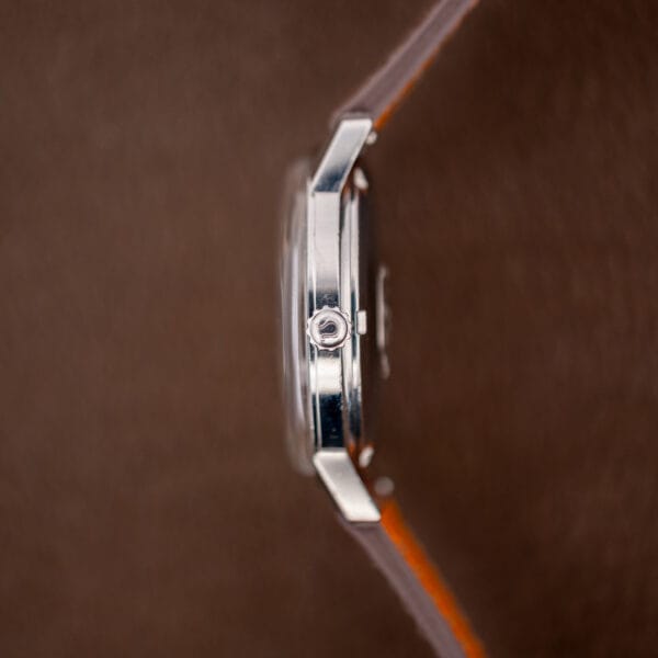 Omega 165.002 case profile showing the signed Omega crown and slim polished stainless steel case band