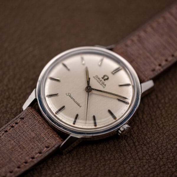 Omega Seamaster 165.002 three quarter view, applied baton markers catching light across the silver dial