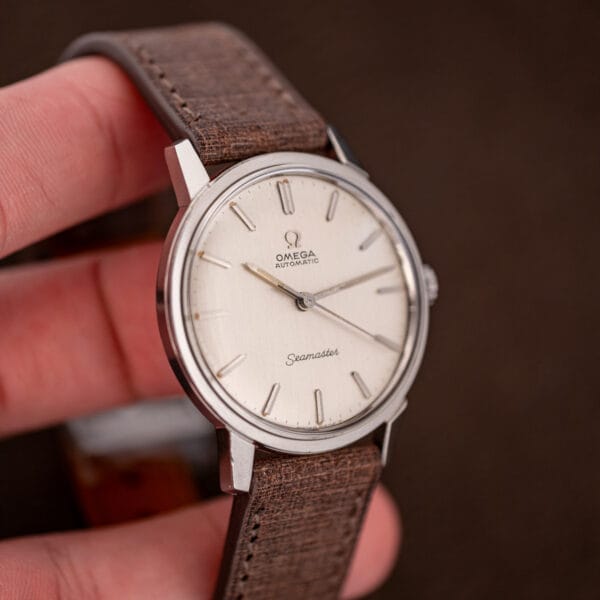 Omega Seamaster 165.002 held in hand showing 34.5mm stainless case proportions and silver dial