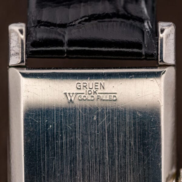 Macro of Gruen caseback stamping reading GRUEN 10K GOLD FILLED above the Wadsworth W case maker mark