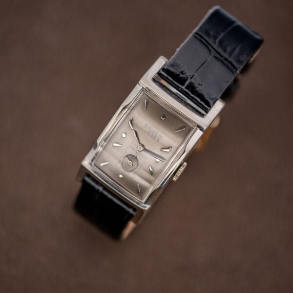 Vintage Gruen Curvex Precision 370-650 photographed at a steep angle with the black leather strap curling below