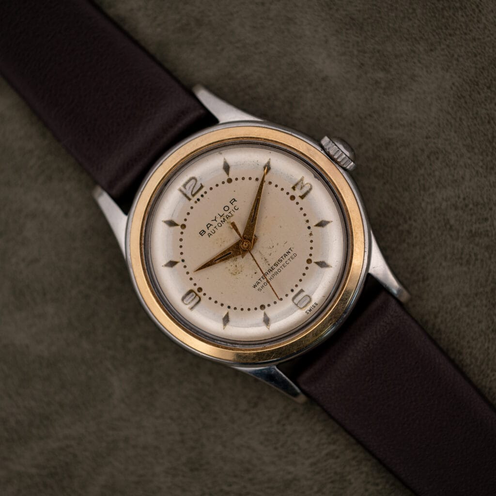 Vintage Baylor Automatic cream dial with applied gilt numerals and yellow bezel ring on a leather strap