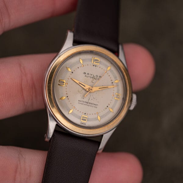 Vintage Baylor Automatic held in hand, cream dial with age spotting and faceted lozenge hour markers