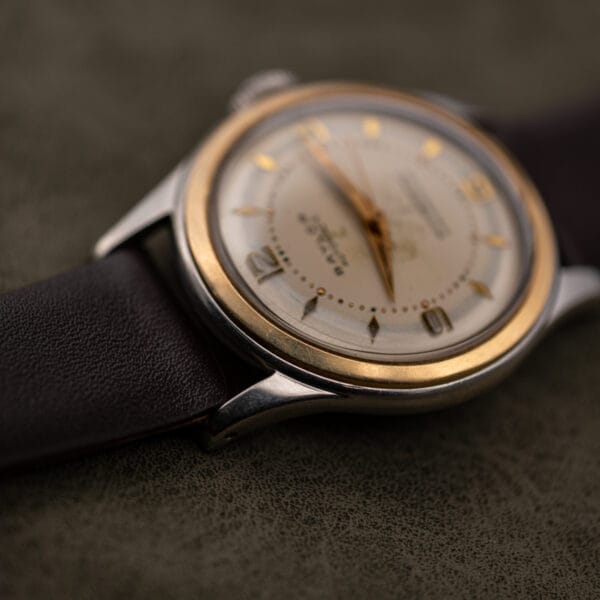 Macro of the Baylor Automatic bezel and lug line with the aged cream dial soft in the background