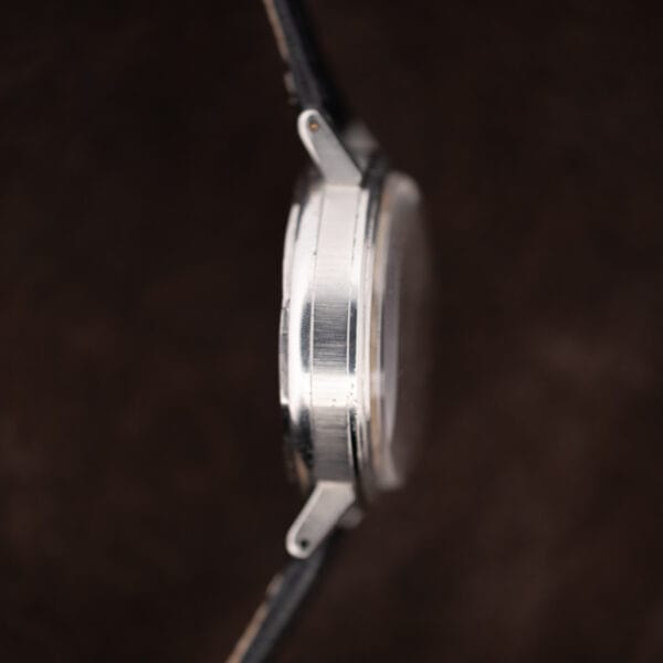 Opposite case flank of the Movado 14819 showing a plain polished steel band with no correctors on this side