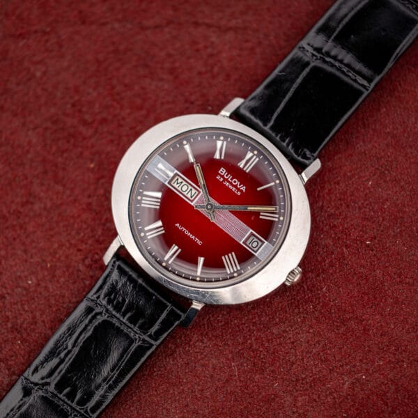 Bulova President C day/date automatic on black alligator-grain leather, maroon dial lit at its center