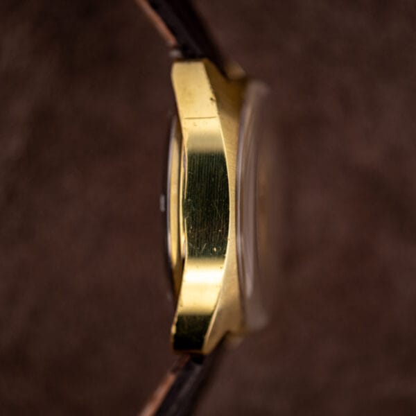 Side profile of the gold plated cushion case, domed acrylic crystal standing proud above the bezel