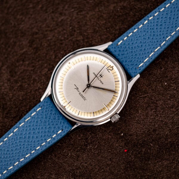 Vintage Hamilton Thin-O-Matic watch angled to show polished steel case, fluted crown and blue leather strap