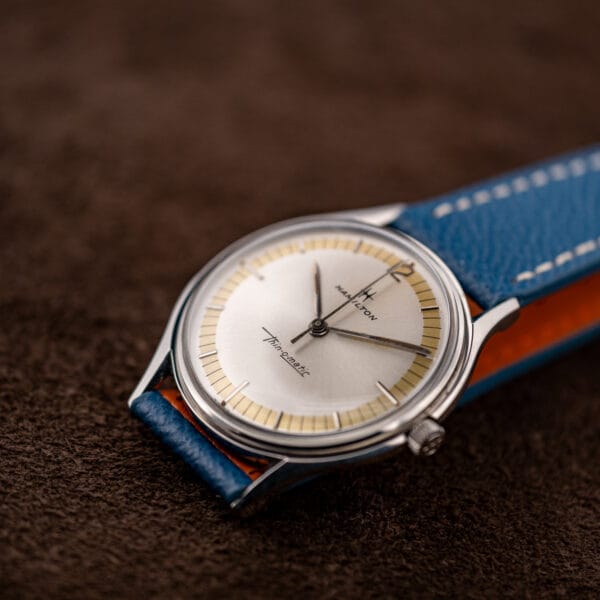 Hamilton Thin-O-Matic at low angle showing faceted downturned lugs and the tan lining of its blue strap