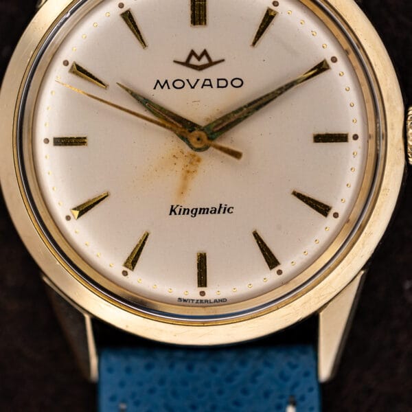 Close view of the warm white Kingmatic dial with faceted dauphine hands and aged lume channels