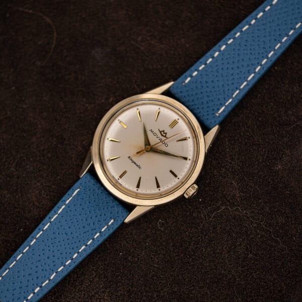 Movado Kingmatic photographed on brown suede with the blue strap running across the frame