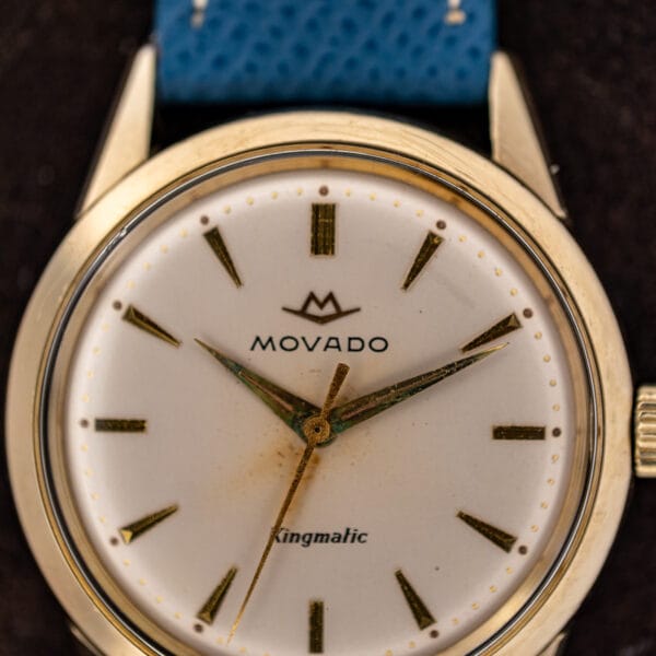 Macro of the Movado Kingmatic dial showing the chevron logo, ribbed quarter batons and dart markers
