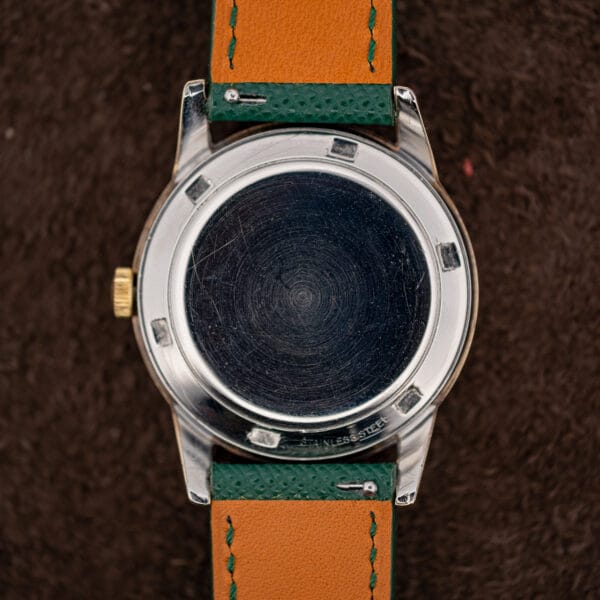 Movado Kingmatic snap caseback stamped STAINLESS STEEL beneath the gold capped case with six pry notches around the rim