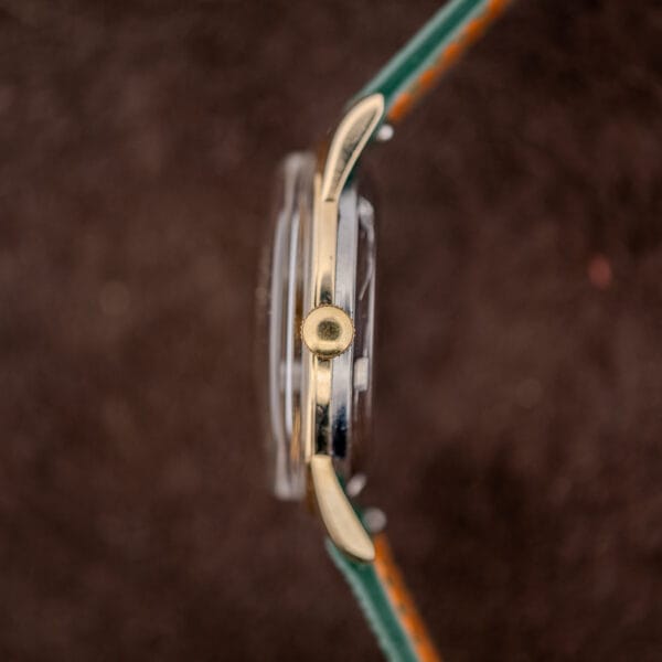 Movado Kingmatic case profile showing reeded gold crown and the steel caseback band beneath the gold capped mid case