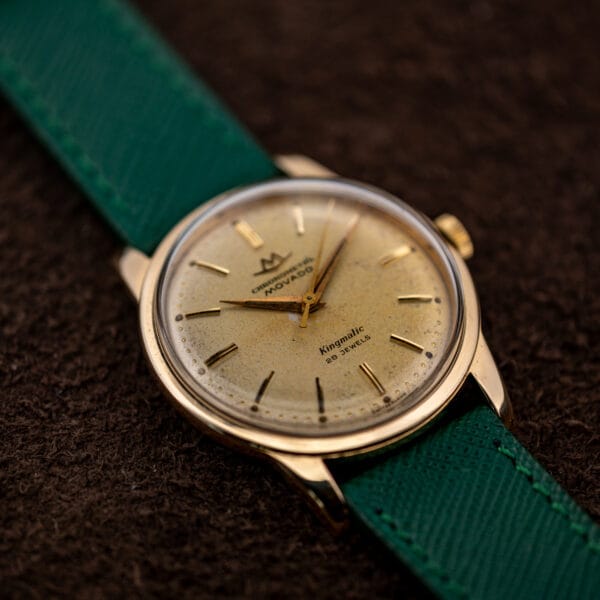 Movado Chronometre Kingmatic three quarter view with gold capped case, green saffiano strap and crown at upper right
