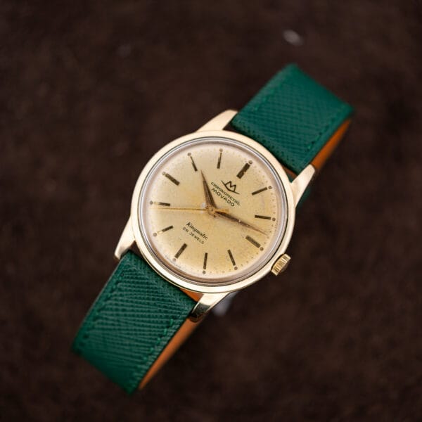 Movado Chronometre Kingmatic resting on its green saffiano strap with the champagne dial catching soft studio light