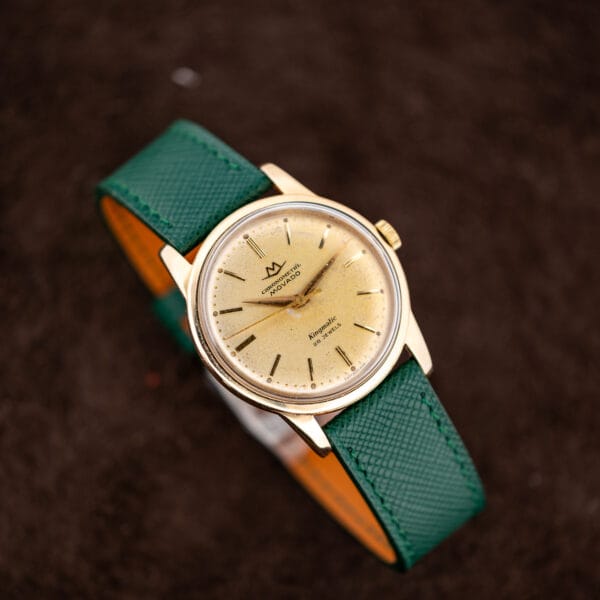 Movado Kingmatic 15072 with green saffiano strap sweeping across frame and gold capped case in three quarter view