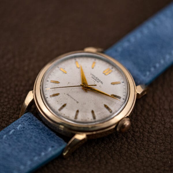 Angled view of the Universal Genève automatic resting on its powder blue Italian suede strap