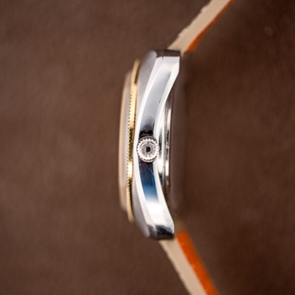 Signed Longines crown with the winged hourglass emblem beside the fluted gold bezel