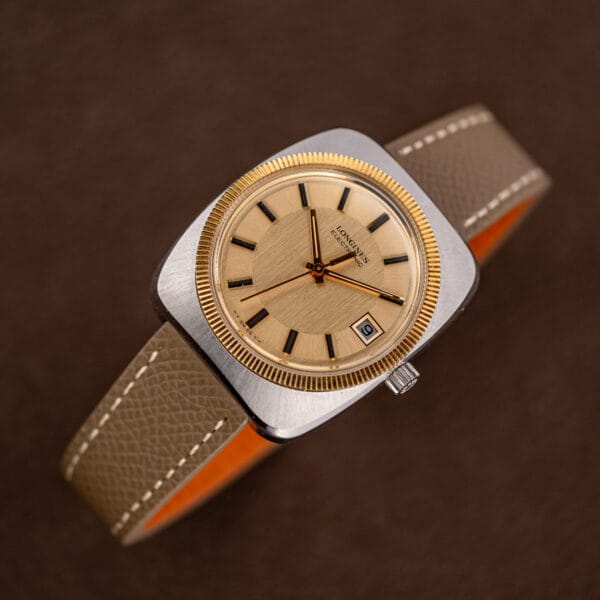 Tilted view of the champagne dial and gold fluted bezel, Longines Electronic on leather