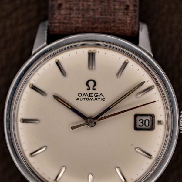 White dial with applied faceted baton markers, doubled marker at 12 and framed date window at 3