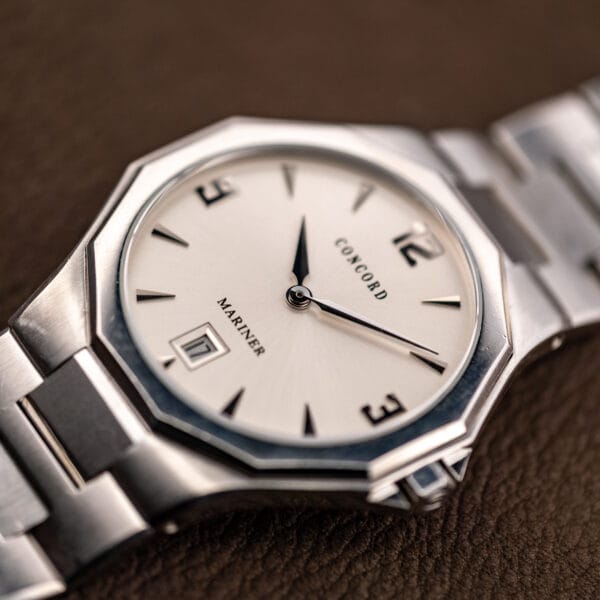 Three-quarter angle catching the radial sunburst finish sweeping out from the center of the silver dial