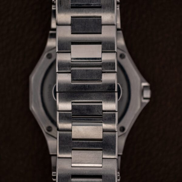 Reverse of the watch with the bracelet curving away and the four caseback screws visible