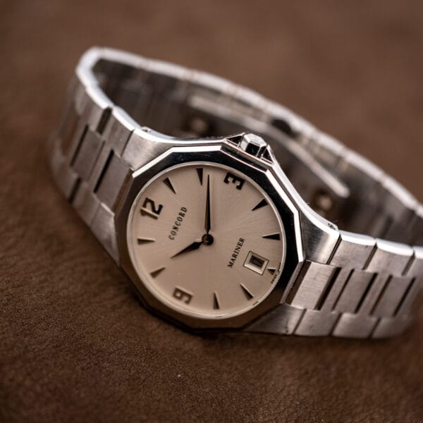 Case flank where the bracelet meets the steel case, with the crown seated in its guard at three