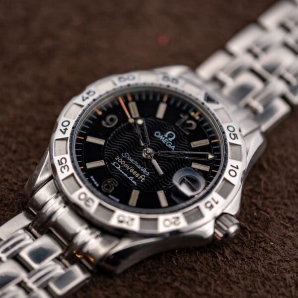Angled view of the Omega Seamaster Autoquartz black wave dial with applied luminous batons and magnified date window.