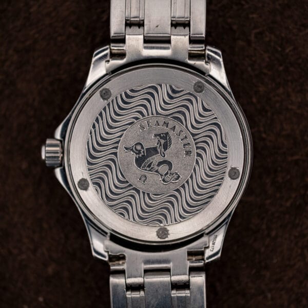 Screwed caseback of the Omega Seamaster showing the hippocampus medallion set into an engraved wave pattern.
