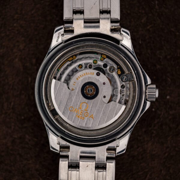 Omega caliber 1400 in the case with its oscillating rotor and green electronic components visible beneath.