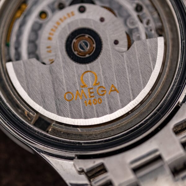 Macro of the rotor signed Omega 1400 in gold, the winding weight that charges the quartz movement.