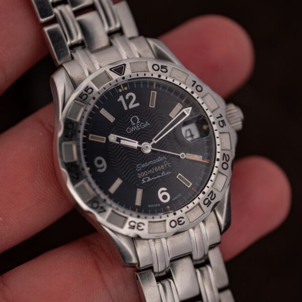 The Seamaster Autoquartz held in hand at an angle, bezel and crown catching the light.
