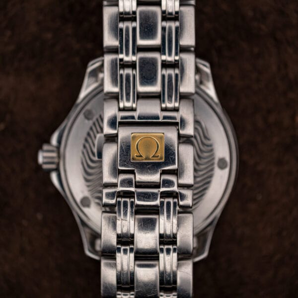Folding clasp of the steel bracelet with its applied Omega symbol plaque, scratched from years of wear.