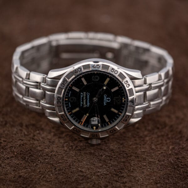 The complete Omega Seamaster Autoquartz standing on its bracelet, dial turned away, on textured brown suede.