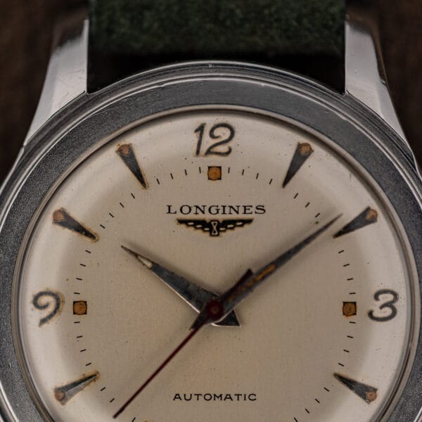 Macro of the Longines 6280-5 dial showing applied 12, 3 and 9 numerals with amber-aged lume plots