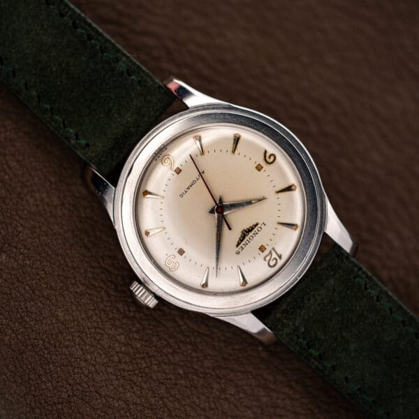 Angled view of the Longines 6280-5 showing its domed acrylic crystal, stepped steel case and green suede strap